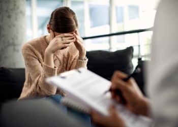 Sad woman holding her head in pain while having a meeting with psychotherapist.